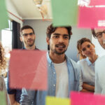 Shot of a group of businesspeople brainstorming with notes on glass wall in an office